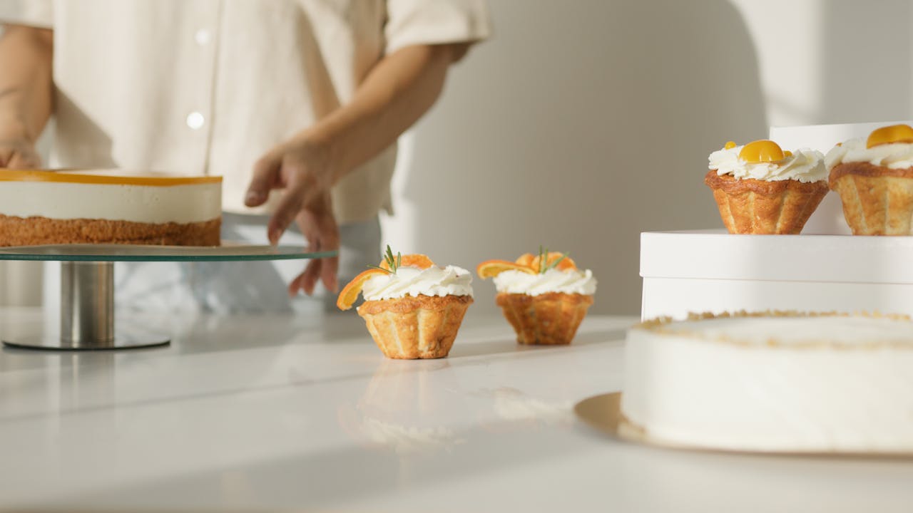 Handmade cupcakes and cheesecake on display with a baker's touch, creating a fresh, delightful atmosphere.